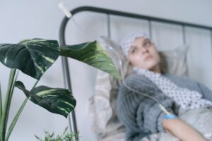 A young woman with a headscarf receiving chemotherapy treatment through an IV line while lying in a hospital bed.